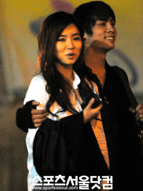韓国アイドルグループ「SHINee」ジョンヒョンが韓国女優シン・セギョンの肩を抱いて二人とも笑顔で歩いている画像。